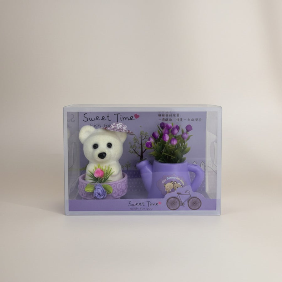 eRamis white teddy bear with purple hat and pink flower, next to a purple watering can with purple flowers.