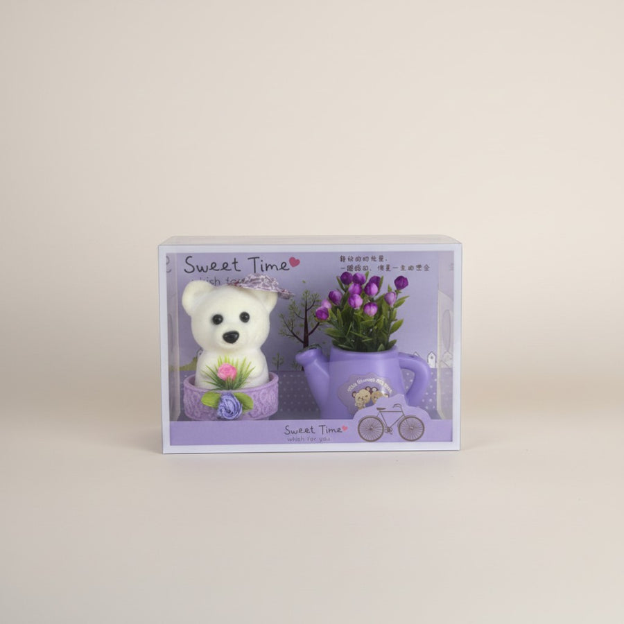 eRamis white teddy bear with purple hat and pink flower, next to a purple watering can with purple flowers.