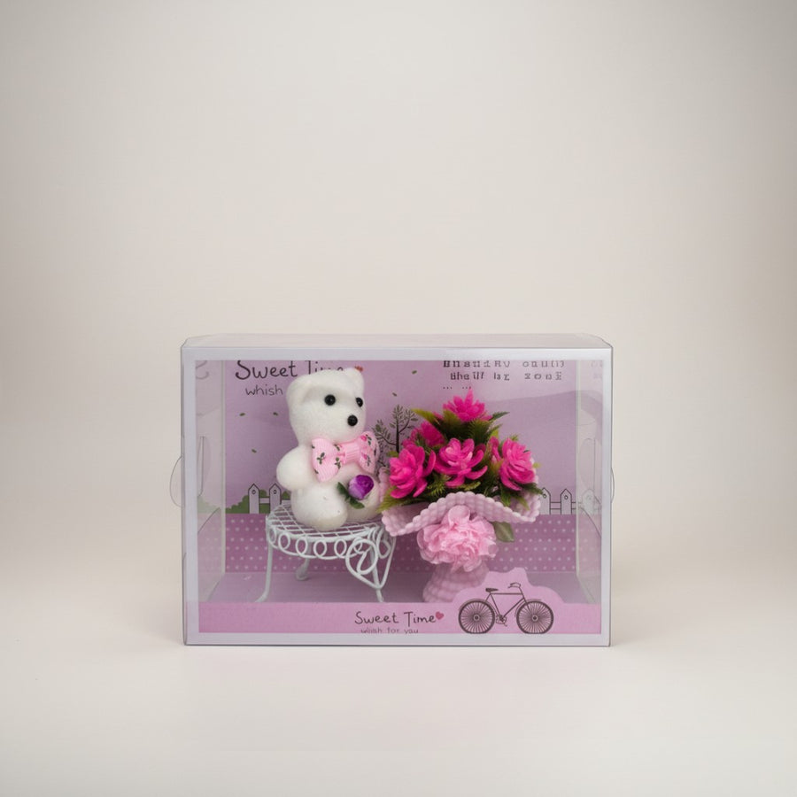eRamis white teddy bear with pink bow sitting on a white bench next to a bouquet of pink flowers in a vase.