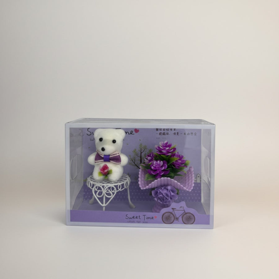 eRamis white teddy bear with purple bow and rose, sitting on a white chair next to purple flowers.