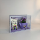 eRamis white teddy bear with purple hat and pink flower, next to a purple watering can with purple flowers.